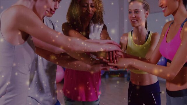 Workout group placing palms together in fitness studio near hoops stacking and lifting celebrating