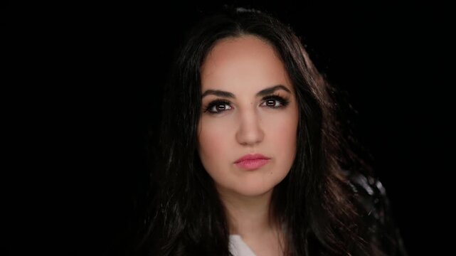 Authenticity and self-esteem A young woman looks directly at the camera with a confident expression against a black backdrop in a studio setting.