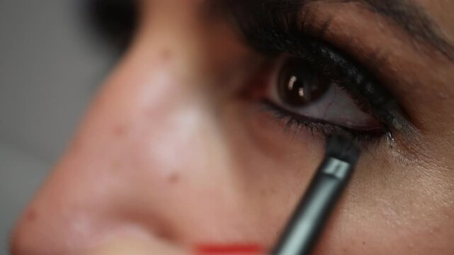 Beauty and self-care A close-up shot shows a woman applying eyeliner with a brush makeup tutorials beauty product commercials or documentaries about the beauty industry The slow-motion footage.