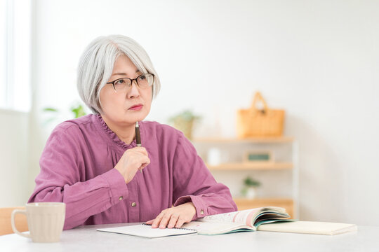 A senior woman studying while looking at textbooks.