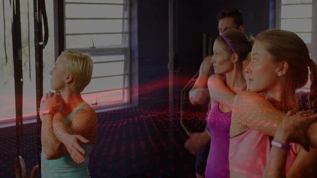 Teal lead initiating group doing crossarm stretch warmup at gym red dot laser sweeping across group