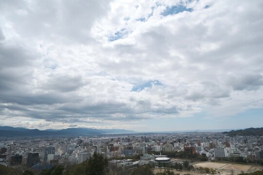 Panoramic cityscape with coastal view under a dramatic cloudy sky