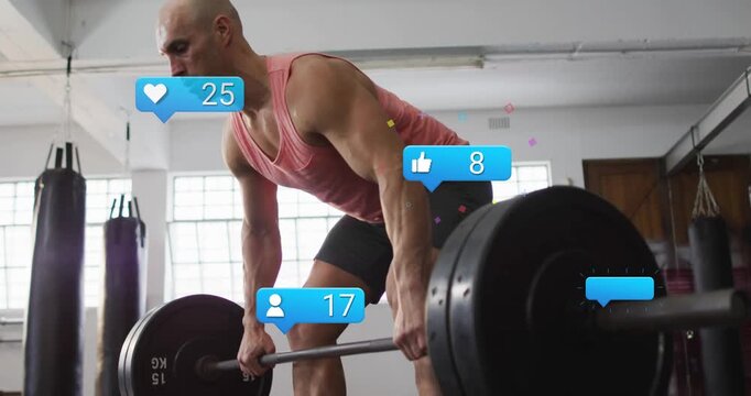 Male athlete gripping barbell, doing slow lifts in fitness gym, social icons updating to track reps