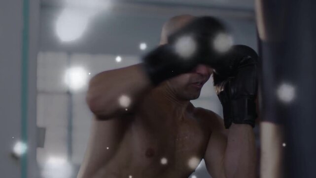 Male boxer starting training holding guard and throwing punches at heavy bag with flares crossing