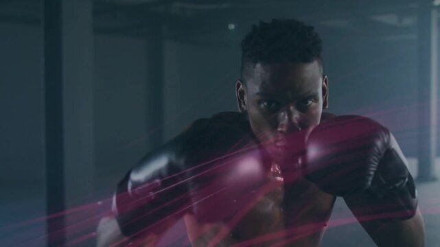 Vertical video: Starting guard, shirtless boxer punching combos in gym, black gloves pink trails