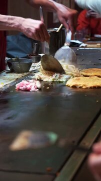 Authentic Japanese savory pancake cooking on a teppan grill