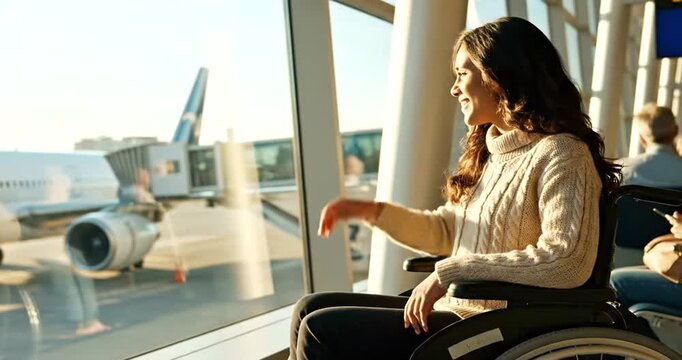 Woman in airport lounge looking out window at airplane on tarmac with luggage
