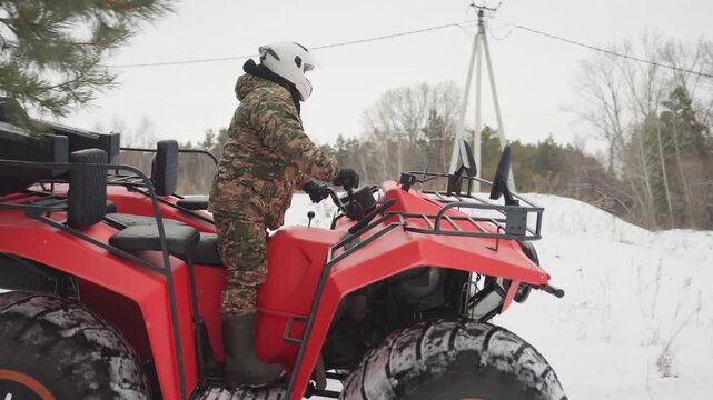 Red quad atv in snowy forest, camo rider mounts and powers machine, heavy tread tires bite into fresh snow, engine revs and exhaust steam, close framing highlights grip and control, hunterstyle