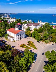 Obraz premium Aerial view of a seaside city square with ornate buildings, trees, and expansive blue sea