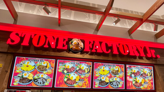 STONE FACTORY Jr. restaurant with illuminated red sign and digital menu boards displaying Japanese hamburg steak and ishiyaki beef meals - Osaka, Japan, September 23, 2024
