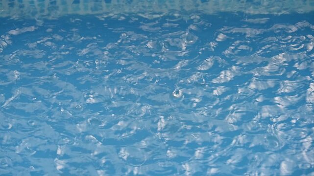 close up of blue water in swimming pool with rain drops