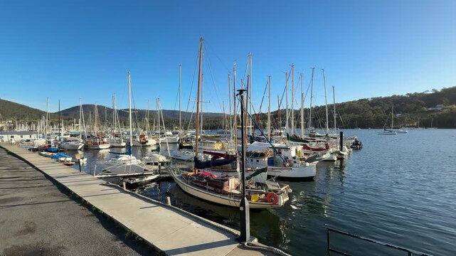Sailboats and yachts moored at Kettering Ferry Terminal in Tasmania, Australia. Scenic waterfront marina and gateway to Bruny Island on a clear day.