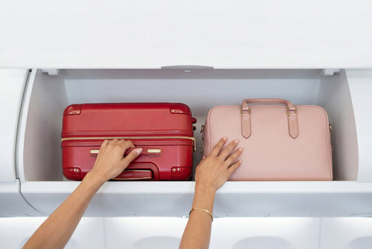 Passenger putting luggage into airplane overhead bin