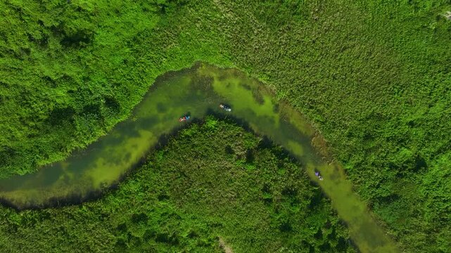 Scenic drone shot of Trang An UNESCO heritage site with winding river and dramatic karst formations.
