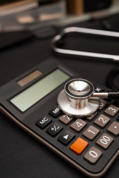 Stethoscope and Calculator on Black Background Representing Healthcare Costs and Financial Planning. Medical expenses, health insurance, financial budgeting for healthcare, and medical industry.