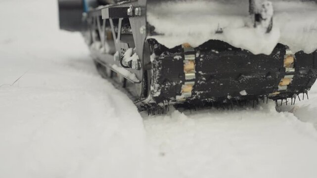 Atv track carving fresh snow leaving deep tread groove, closeup of rubber and metal components with snow spray, lowangle macro of traction and movement on frozen pine trail, subtle track marks fading