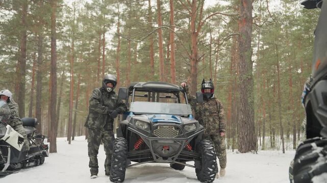 Snowy forest atv convoy preparing riders in camouflage gear, sidebyside utv and snowmobile parked among tall pines, helmets on, engines idling, breath visible in cold, team checks winch and suspension