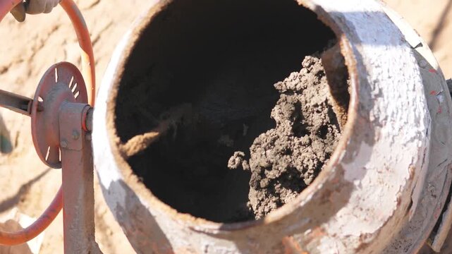 Concrete Residue Clinging To Mixer Interior During Construction Maintenance Check, Technician Surveys Hardened Patches And Paddles, Closeup Of Crust And Drum Surface Before Cleanup.