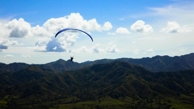 Skydiver paragliding flying over a mountains