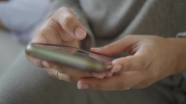 Close up shot of woman hands holding smartphone and scrolling on touch screen with finger.