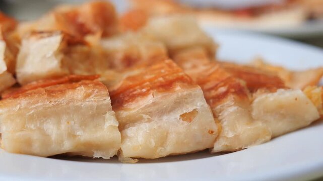 Freshly baked turkish borek with cheese served on white plate closeup.