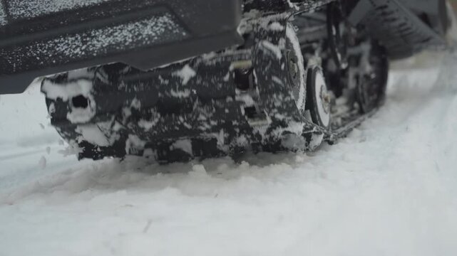 Lowangle snowmobile track carving powder snow across pine forest trail, closeup of rubber tread throwing frozen spray, slowmotion grit and vibration, mechanical power delivering traction across uneven