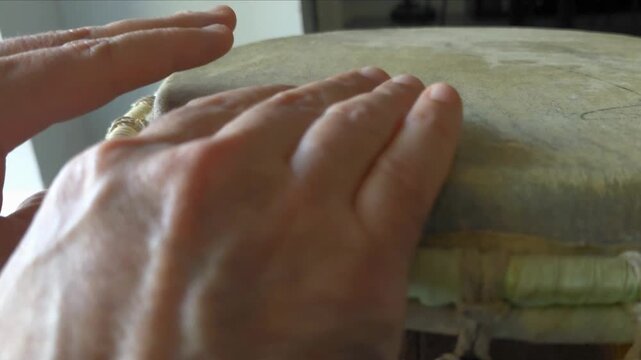 Close up of hands playing a traditional wooden Djembe drum