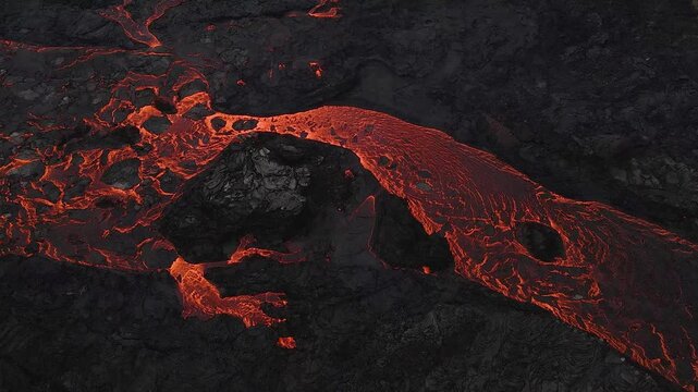 Aerial view of flowing hot lava stream creating intricate patterns on dark volcanic rock surface