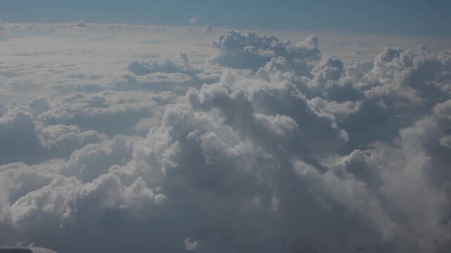 Massive cumulus clouds above horizon in flight, calm high altitude view, soft cloud shapes in daylight creating a sense of air and space