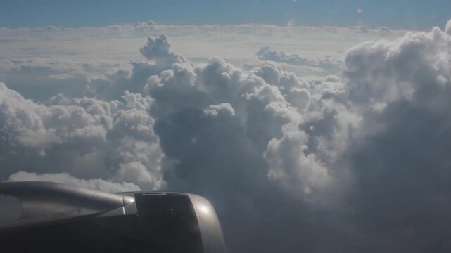 Airplane engine beside tall cumulus clouds in flight, peaceful high altitude view with soft cloud formations and daylight atmosphere creating a sense of openness and air