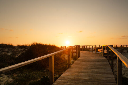 Wooden path at Costa Nova d'Aveiro, Portugal, over sand dunes with ocean view, evening. Wooden footbridge of Costa Nova beach . Aveiro, Portugal.