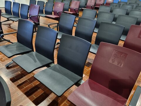 Priority seating for elderly and disabled passengers in an airport waiting hall with red chair.