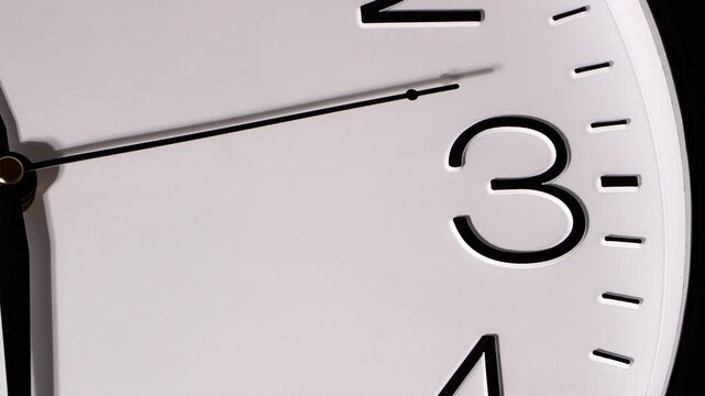 Closeup of analog clock face pointing toward number three