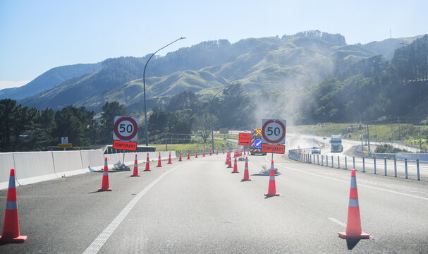 50km/h road sign and traffic cones at Transmission Gully. Unrecognizable workers working on the motorway. Wellington.