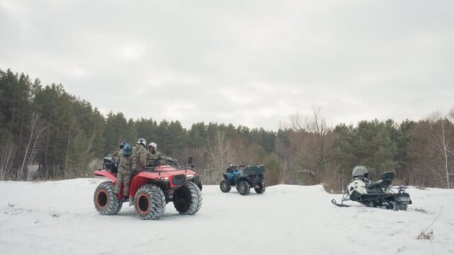 Machines await at pine edge silently tensing. Revving engines on snow as riders readiness builds up. Capturing intense moment of ATV engines revving in winterly stillness with anticipation