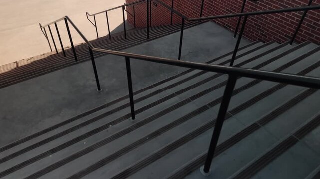 Slow descending glide over outdoor concrete steps and railings with strong sun and shadows