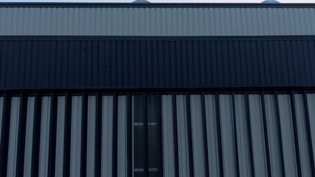 Closeup aerial shot of corrugated metal cladding on a large industrial warehouse. Ideal for construction, engineering, and logistics industry projects.
