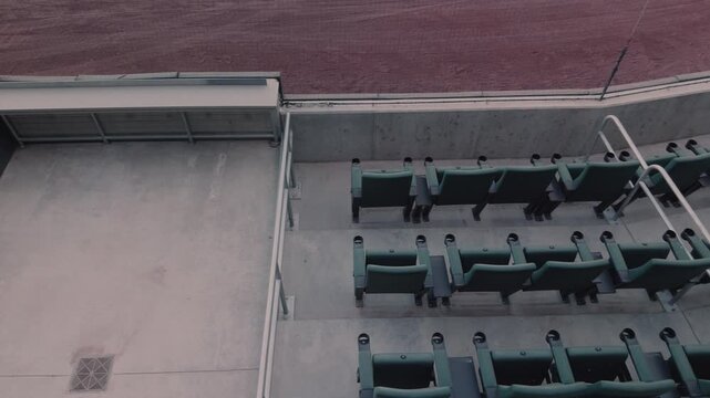 Steady left to right pan across empty lower stadium seating beside baseball field.