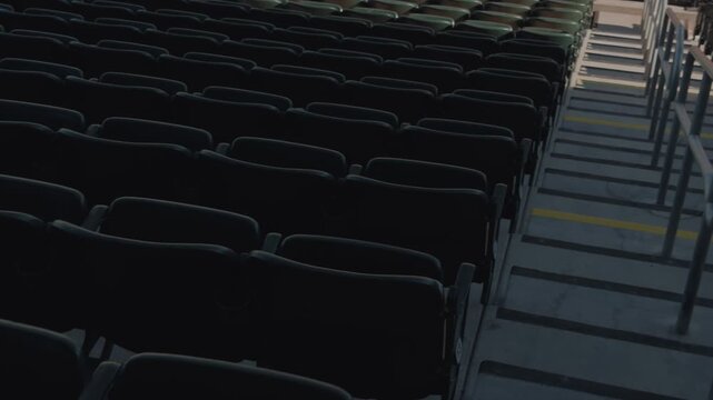 Steady slow pan rising from empty stadium seating and aisle rails to infield dirt and grass