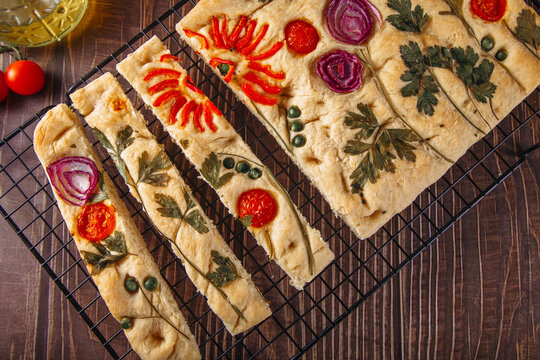 Floral focaccia bread cooling on rack with herb art