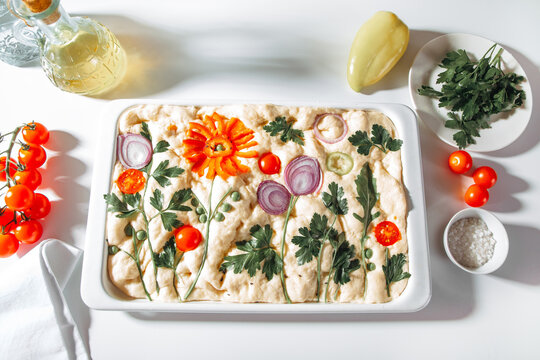 Floral focaccia bread with vegetable art on white table