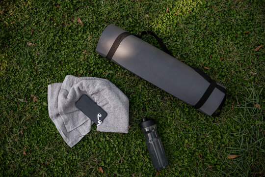 Outdoor yoga essentials on grass with mat towel and bottle
