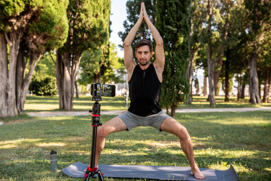 Man practicing yoga outdoors with smartphone on tripod