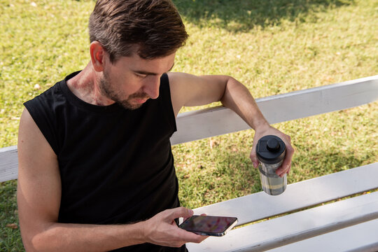 Man in sportwear on bench checking phone after yoga