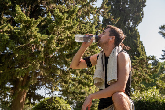 Man hydrating after outdoor yoga workout in sunny park