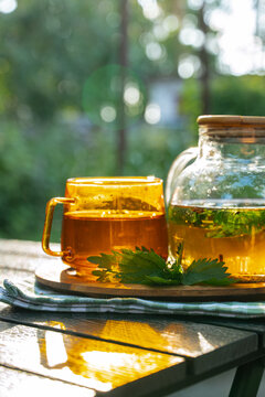 Herbal detox tea in glass cup and teapot on patio table