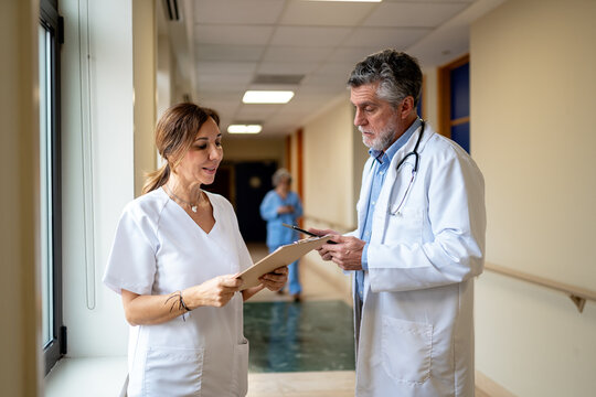 Medical staff discussing patient notes in a hospital hallway