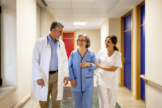 Caring doctors assisting patient in hospital corridor