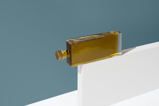 Minimalist glass bottle of olive oil on white pedestal