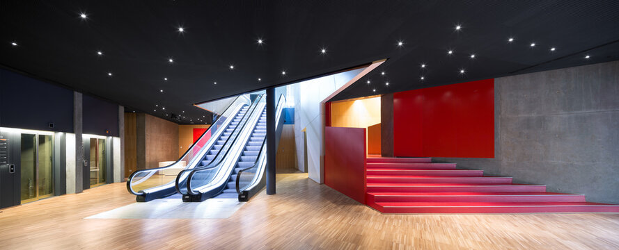 Modern exhibition hall with escalator and red accents